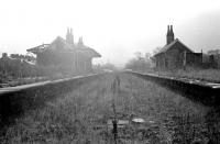 The derelict station at Earby, Lancashire, closed in February 1970. Photograph taken in October 1976 looking south west over the former Salterforth Road level crossing towards Colne. [See image 39293] [Ref query 13081]<br><br>[Ewan Crawford Collection 14/10/1976]