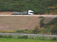 A lorryload of concrete sleepers heads south along the A7 south of Heriot on 18 August 2014. The Borders Railway trackbed awaits delivery in the foreground.<br><br>[Bill Roberton 18/08/2014]