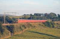 A Class 325 EPU Royal Mail service, comprising units 012, 002 and 003, passes Bay Horse heading for Shieldmuir in the summer evening sunshine on 18 June. 325003 has recently been repainted and the different shade of red (and absence of yellow banding) stands out from the other two units in the train. <br><br>[Mark Bartlett 18/06/2014]