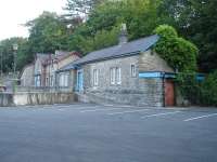 Llangefni station and station house in July 2014. View across the large car park now embracing the old goods yard looking south towards High Street.<br><br>[David Pesterfield 23/07/2014]