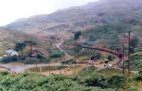 A train on the Ffestiniog Railway, headed by a Double Fairlie locomotive, passing between the level crossings at Tanygrisiau, Gwynedd, in July 1991.<br><br>[Colin McDonald /07/1991]