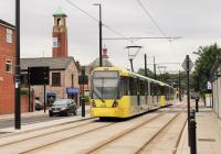 A brace of M5000 series trams approaching Rochdale Railway Station on 7 August along the new section of the Metrolink system from Rochdale Town Centre. They will run via Oldham to Manchester and then out to East Didsbury. The fire station and its prominent tower are still for sale! [See image 34125]<br><br>[Mark Bartlett 07/08/2014]