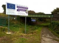 A sign, a sign, give us a sign: the only evidence so far to be seen from road level, that a new station will shortly be built next to the Bermuda industrial park. The solum beneath the bridge is an abandoned branch from the Coventry canal. Nuneaton is to the left, Coventry to the right [see image 31064].<br><br>[Ken Strachan 12/10/2014]