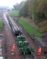 The first main line train to reach the solum of the Waverley Route since the last track-lifting train passed through in late 1972. Just after 14.30 on a wet Monday 13th October 2014, GBRf 66736 propels the tracklaying train through Kingsgate Points where the new Borders Railway alignment via Shawfair joins the original route from Millerhill through the trees to the right.<br><br>[David Spaven 13/10/2014]