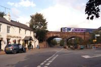 A Carlisle to Leeds service crosses the red sandstone viaduct at the south end of Lazonby & Kirkoswald station on 6 September 2014 with the Hotel on the left giving a clue to the railway company that built the line. [Ref query 6934]<br><br>[John McIntyre 06/09/2014]