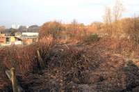 Looking north along the trackbed at the site of Broomhouse station (closed 1927) in November 2014 towards the point  where it crossed the Rutherglen and Coatbridge line at Mount Vernon (South). The line closed completely in the 1960s. The recently installed OHLE on the current Whifflet line is visible above the buildings on the left. Little trace of the former railway from Shettleston to Hamilton remains and now Broomhouse station site is being excavated for a new road alignment.<br><br>[Colin McDonald /11/2014]