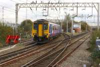 A Northern service to Manchester Oxford Road from Liverpool takes the Warrington Central route at Allerton Junction on 4 November 2014. The building amongst the trees on the left houses the Allerton Depot wheel lathe.<br><br>[John McIntyre 04/11/2014]
