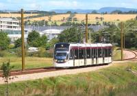 A city bound tram climbs away from Edinburgh Airport on the morning of Sunday 13 July 2014. Long lens shot taken from the platform at Ingliston Park and Ride.<br><br>[John Furnevel 13/07/2014]
