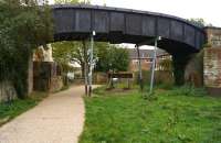 The trackbed into the station site at Blandford Forum on 22 October 2014 with the footbridge over the trackbed supporting a smoke deflector - although a local source suggested that this had been added as part of the 'recreation' along with the buffer stop underneath.<br><br>[John McIntyre 22/10/2014]