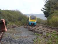 Arriva 175102 leans into the curve after passing Kidwelly level crossing heading east towards Swansea with the 13.01 service from Carmarthan to Manchester Piccadilly in October 2012. The overgrown and rusting Gwendraeth Valley line exchange sidings are on the left, with part of the head shunt stop block just visible.<br><br>[David Pesterfield 31/10/2012]