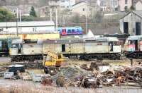 A tired and well worn 47368 stands in the scrap and recovery area at Carnforth Depot on 5 January 2015. The ex-Fragonset Brush 4 was purchased by West Coast in late 2006 but hasn't run since and is slowly losing its components to other West Coast operational locos. [See image 40169] A Barrow bound TPE 185 runs past the site in the background.<br><br>[Mark Bartlett 05/01/2015]