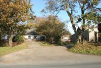 View east across the B9006 Station Road in Ardersier in October 2005 showing the former Fort George station building, now a much modified private residence. The old goods yard, currently used by a building firm, stands on the right with the large goods shed still intact.<br><br>[John Furnevel 31/10/2005]