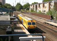 Some of the many changes that have taken place at Kensington Olympia in the preceeding 25 years or so [see image 37691] are shown in this photograph taken in July 2005, with an inspection unit standing at platform 2. The sidings and bays on the east side have now gone, with the through tracks reduced from 4 to 3 and a new, shorter, through platform constructed (the old platform now supports the fence). The land released has become a new 'street' standing between the station and Russell Road, consisting of blocks of flats in the 'non-trivial' price category. The former west side bays (the large blue shed and the area beyond), following several years as London's main Motorail terminal, now house 'Olympia Parking'. View is north towards Willesden Junction with Kensington High Street behind the camera. <br><br>[John Furnevel 21/07/2005]