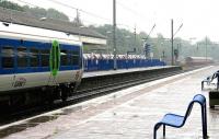 Looking east from platform 1 at Ealing Broadway in the rain in July 2005 as a main line service waits to leave for Paddington.  In the right background a Central line train is approaching the platforms, with a District line train appearing out of the mist just beyond.<br><br>[John Furnevel 20/07/2005]