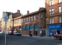 Standing between the tenements of London Road is the former Bridgeton Central station, closed in 1979 and now (2005) a bookies. The Station Bar remains alongside as a reminder of times past. [Editor's note: The 99p breakfast menu at neighbouring Scooby Snacks, as advertised on the post, consists of, sausage, bacon, tattie scone, egg, black pudding, beans, fried tomato and a slice of bread!]<br><br>[John Furnevel //2005]