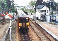 A northbound train for Inverness leaving Kingussie station via the level crossing over the B970 Ruthven Road on 12 September 2004. Kingussie High School stands in the right background.<br><br>[John Furnevel 12/09/2004]