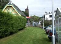 Remains of Moffat station in July 2004. Looking north past the relocated former station toilet block towards the buffer stops and the town centre, with cars parked along the platform edge in what is now part of the car park of the local supermarket. [See image 19320]<br><br>[John Furnevel 30/07/2004]