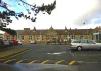 There's no need to take the hump. Carnforth station building - carrying the significant addendum 'and Heritage Centre' is sandwiched between a car park speed bump and a tree branch in this view taken from a rather breezy bus stop in January 2015. [See image 27391]<br><br>[Ken Strachan 28/01/2015]