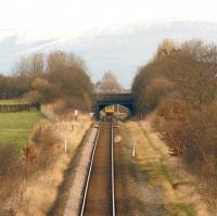 Peeping under the road bridge carrying the A583 to Blackpool, a Class 142 has just left the junction at Kirkham as it heads to Blackpool South on 2 February 2015. In the background the Bowland fells have a light covering of snow. [Ref query 6878]<br><br>[John McIntyre 02/02/2013]