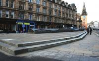 Unconcerned by the sound of a fast approaching Motherwell train, pedestrians stroll casually past the site of the former Glasgow Cross station on 31 January 2015. The curved structure acts as a ventilation grille for the Argyle line below.	<br><br>[Colin McDonald 31/01/2015]