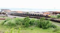 Looking across Leith South yard towards the Firth of Forth on 9 June 2005 as a train of empty coal hoppers is propelled towards the docks. The locomotive carrying out the manoeuvre is EWS 66078. On the nearer line pipes are being trans-shipped from rail to road transport.<br><br>[John Furnevel 09/06/2005]