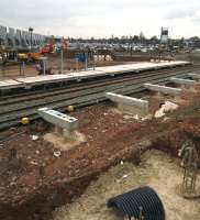 Looking South East over the new Coventry Arena station on 15 March with rapid progress evident. There are fence posts on the southbound platform, supports for the northbound platform and, in the foreground, a possible new pedestrian entrance. The popularity of the shopping centre can be gauged by the full car park in the background. [See image 50538],<br><br>[Ken Strachan 15/03/2015]