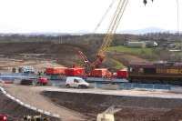 66158 hauling a Hunterston-Longannet coal train passes the Braehead M8 viaduct construction site on 2nd April 2015. The line of the motorway can be seen in the background leading up to the temporary embankments on either side of the track where the piling work for the new railway viaduct is taking place.<br><br>[Colin McDonald 02/04/2015]