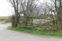 More than fifty years after it was swung across Railway Crossing Lane for the last Glasson Dock goods train this crumbling level crossing gate can still be seen in Aldcliffe near Lancaster in 2015. The cyclepath from Glasson leaves the trackbed at this point but the railway formation continues towards Lancaster for a short distance before being built over. [Ref query 6608]<br><br>[Mark Bartlett 01/04/2015]