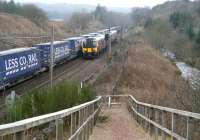 The 14.18 FTPE Edinburgh Waverley - Manchester Airport passing the late running 0616 Daventry - Mossend containers ascending Beattock Bank behind DRS 68002+68004 on 18 March 2015. Travelling at a much more leisurely pace over on the right is the Elvan Water. <br><br>[John Furnevel 18/03/2015]