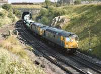 26014 and 26010 emerge from the tunnel below the Union Canal at Craiglockhart Junction with a trainload of pipes in 1982. The train is turning west off the Edinburgh 'sub' and taking the link to Slateford Junction. [Ref query 8094]<br><br>[Bill Roberton //1982]