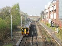 An East Midlands Trains Nottingham to Liverpool Lime Street service passes the Manchester United halt on 24th April 2015. Another EMT 158 on a Lime Street to Norwich service is just coming into view in the distance. In between the two trains is Trafford Park West Junction, which provides access to the container terminal.<br><br>[Mark Bartlett 24/04/2015]