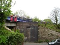 A First Great Western HST, on the slightly late 15.55 departure to Paddington - 14.53 ex Exeter St. David, stands across the bridge carrying the present single line over the A362 Wallbridge, beyond the north end of Frome station, on 8 May 2015. The leading power car is visible to right of a bridge abutment which shows an infilled area where a second track once crossed the road.<br><br>[David Pesterfield 08/05/2015]