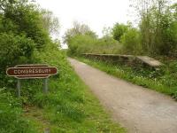 Looking north along what is now cycle route 26 on the trackbed of the former Yatton to Witham Cheddar Valley line in May 2015. Note the almost complete surviving platform running alongside the cycle track for some 100m from just south of the A370 Station Road. A replica station totem has been sited across the trackbed from the south end platform ramp. <br><br>[David Pesterfield 10/05/2015]