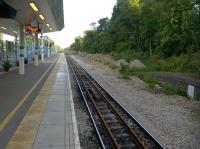 Looking South from the sole platform at the 'new' Corby station in June 2015 there is much of interest. The original down platform on the right is much shorter than the new one, which seems to stop to allow a freight branch to diverge to the left. The piles of ballast and spare rails could be considered to indicate work in progress! [See image 51572]<br><br>[Ken Strachan 07/06/2015]