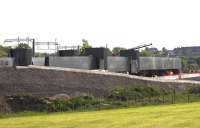 The size of the structure can be appreciated in this view from the south west of the construction site on 12 June. The rectangular grey boxes on the left side of the structure are temporary cabins erected over the locations of the main welds to protect the welders from the elements. Completed welds can be seen to the right. [See image 51623]<br><br>[Colin McDonald 12/06/2015]