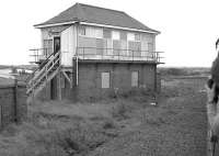 The signal box at Byrehill Junction in August 1985, taken from the window of a special approaching from Dubbs Junction heading for Ayr. Signalman George Stewart is standing at the door of the box, which closed in 1986. [Ref query 6888]  <br><br>[Bill Roberton 31/08/1985]