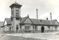 The road approach to Ardrossan North station, viewed from the south east on 24 May 1960. The tall chimneys in the background are part of the large Shell refinery on the west side of the line [see image 23867]. By this time the station had been closed to passengers for some 28 years (July 1932). Demolition of the building would be completed by 1965, with the site subsequently used for lorry/coach parking.<br><br>[G H Robin collection by courtesy of the Mitchell Library, Glasgow 24/05/1960]