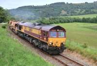 A cheery toot of the horn and a thumbs up from the cab of 66104 as it climbs away from the site of Fodderty Junction on 21 June with five ballast hoppers for Garve.<br><br>[John Gray 21/06/2015]