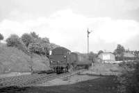 A train of empty stock on its way from East Kilbride to Glasgow passing through Clarkston on 5 June 1964 hauled by a BR Standard tank. The large shed in the recently lifted goods yard is thought to have housed the horse bus and later the motor bus which once connected the station with the village of Eaglesham.     <br><br>[John Robin 05/06/1964]
