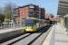 Metrolink 3011 calls at Didsbury Village on an East Didsbury to Rochdale service in April 2015. Didsbury railway station, previously just beyond the bridge, closed in 1967 but rail borne services returned 46 years later with the opening of the East Didsbury tram line in 2013. <br><br>[Mark Bartlett 20/04/2015]
