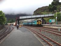 The 1457 scheduled departure from Blaenau Ffestiniog awaits the arrival of the 1445 ex Porthmadog under a heavy sky on 20 July 2015.<br><br>[Bruce McCartney 20/07/2015]
