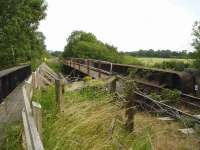 There are two adjacent rail over-bridges that cross the Trent & Mersey Canal and Whatcroft Lane, midway between Middlewich and Northwich. View looking south across the canal bridge, in July 2015, from a walkway created along the former up side bridge decks, with the road bridge just visible to the right through the railings on the canal bridge. [See image 52044] <br><br>[David Pesterfield 16/07/2015]