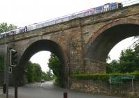 Odd man out. A motor car heads south on the A7 towards Galashiels during a shower of rain on 24 July 2015, having just cleared the southernmost of the 23 arches of Newbattle Viaduct. This arch differs from its 22 Neighbours in being skewed to accommodate the road and incorporating a stone arch ring, as opposed to the brick structures used elsewhere. Overhead a ScotRail 158 is crossing the viaduct on its way to Tweedbank.<br><br>[John Furnevel 24/07/2015]