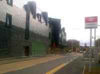 Looking north along the A7 Ladhope Vale, Galashiels, on 20 August 2015, with the new Transport Interchange on the left. The building was officially opened on 6 August and is now operational as a bus station. The pedestrian crossing will eventually link the Interchange with the new railway station opposite.<br><br>[John Yellowlees 20/08/2015]