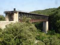 A double deck steel bridge still spans Le Tech river at Le Pont Reynes, on the abandoned section, beyond Ceret, of the branch line from Elnes to Arles-sur-Tech. The upper rail deck extensions have been cut back to the bridge parapets, and the lower deck is now part of a long distance cycle track that uses long sections of the trackbed.<br><br>[David Pesterfield 03/08/2015]