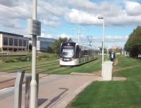 A city-bound tram crosses one of the pleasing grassed-over stretches of track on the approach to Edinburgh Park Central in August 2015. Big money around here: Wall Street, EH12. Your photographer was in the area for a job interview. There is no connection between the previous 2 statements.<br>
<br><br>[David Panton 25/08/2015]