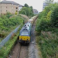 I was approaching the bus stop, as was my bus, when I heard a rumble from the Powderhall branch below. I managed to catch both, in a manner of speaking. 67 010 retuns with the empties in mid-afternoon. Though the platforms of Easter Road in the foreground are still there they are completely overgrown.<br><br>[David Panton 22/09/2015]