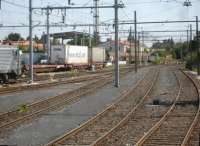 A RegioRail shunting loco hauls a rake of covered  steel carriers out of the general transhipment yard, to the north of the east yard road to rail facility at Le Boulou, that is sited alongside the northbound access slip-road to the A9 E15 autoroute. SNCF Fret electric loco 427029 is seen at left of view [See image 52588].   <br><br>[David Pesterfield 05/08/2015]
