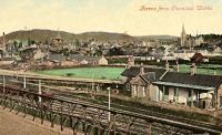 View south to Forres over the first Forres station (1857). This station became surplus when the Inverness and Perth Junction Railway opened from Dunkeld to Forres and a new triangular junction station (1863) was laid out to the west of the original station. The original station seen here was left on a west-east goods loop. The new lines are behind the building. The view was from the North of Scotland Chemical Works, which made sulphuric acid amongst other chemicals, and was rail served. The original station building is long gone and the replacement largely cut back. Postcard in my collection.<br><br>[Ewan Crawford Collection //]