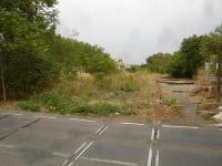 Looking west from Avenue Camille Guerin level crossing in Pezenas, along the mothballed branch line from Adge, showing the twin track section of line that runs from east of the crossing through the former station; the building of which can be seen in the near distance. The building is now in community use. [See image 52653] for view in opposite direction.<br><br>[David Pesterfield 08/08/2015]